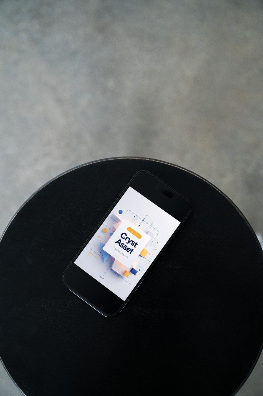 A black smartphone lying on a round black table, displaying a digital wallet or crypto asset interface on its screen against a gray concrete background.