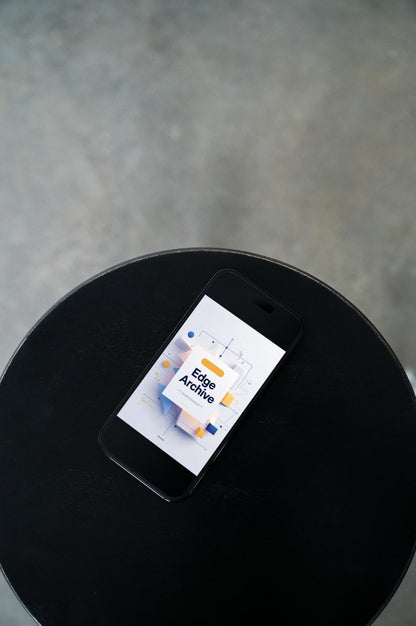A black smartphone lying on a round black table, showing a digital interface with the text 'Edge Archive' on the screen. The background is a textured gray floor.